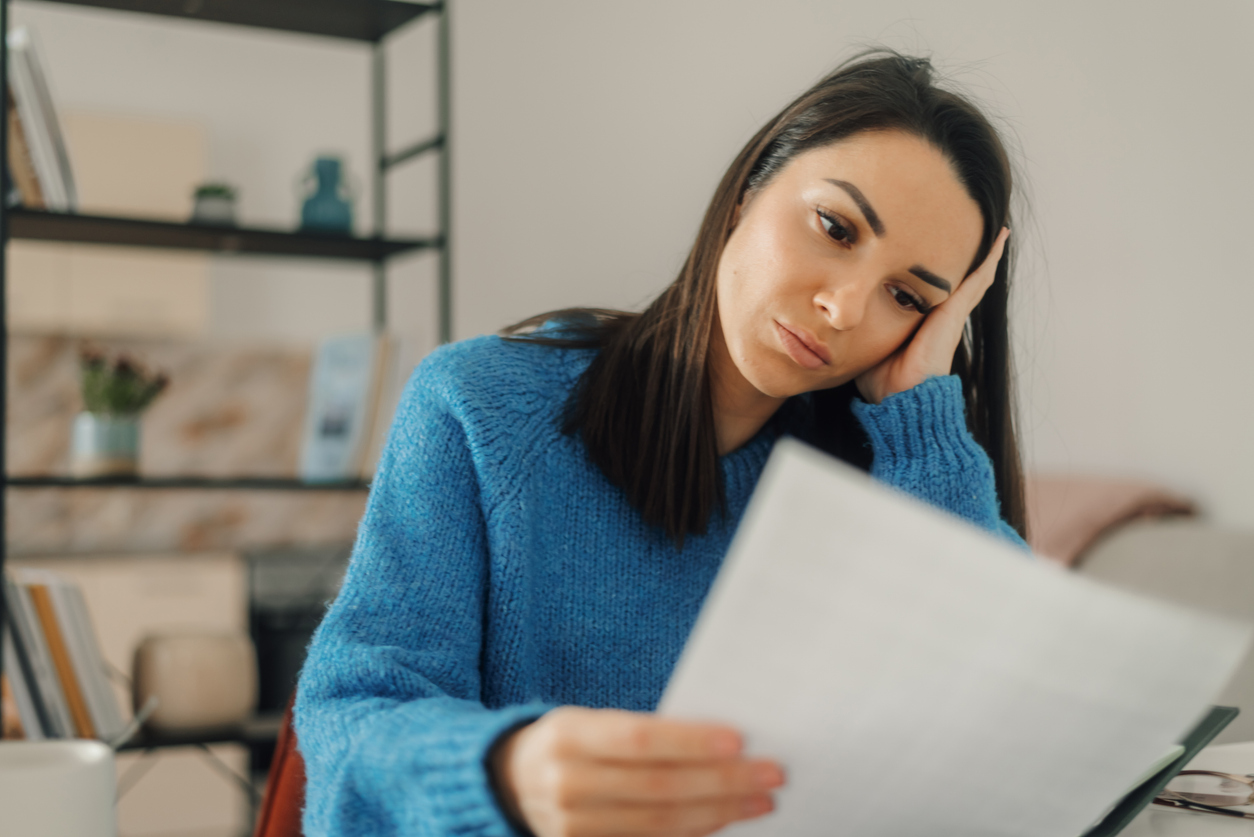 Young woman holding her head while reading a document